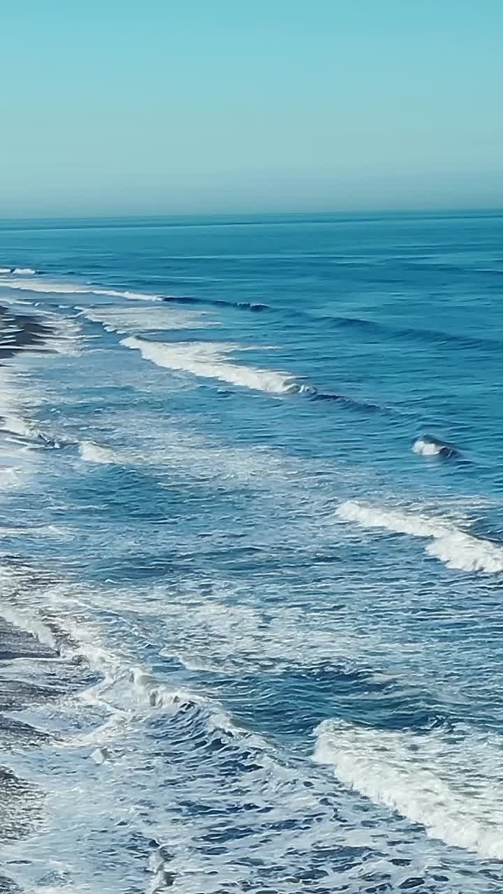 Onde si infrangono sulla riva di una spiaggia in Cile in una giornata limpida