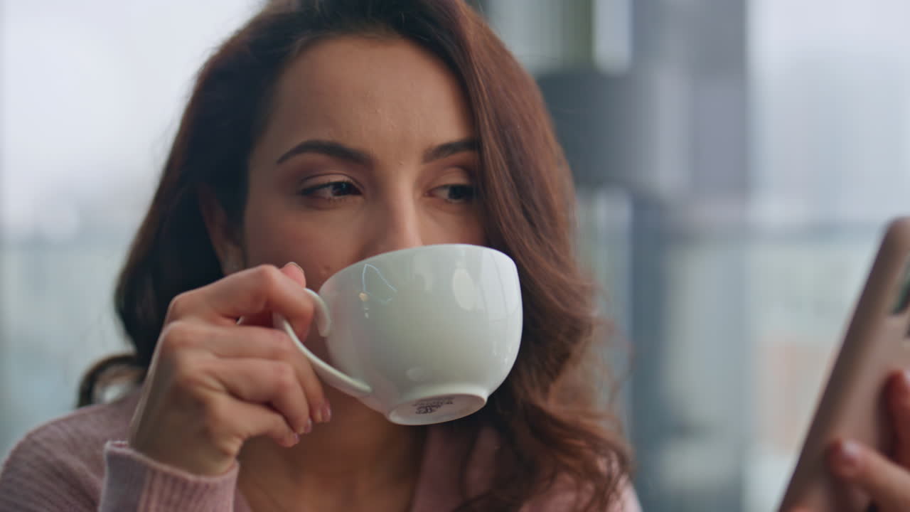 아침에 부에서 드폰 문자를 읽는 여자. 커피를 마시는 여자