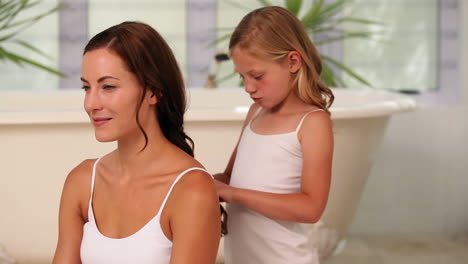 una niña trenzando el cabello de su madre por la mañana