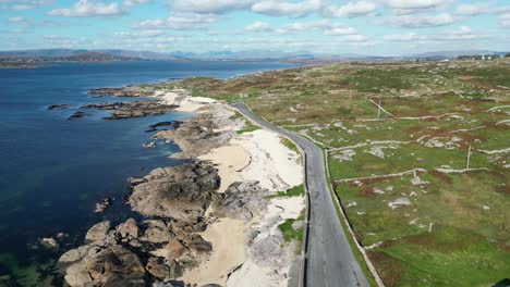 Lowering-drone-shot-of-road-on-the-shoreline-at-Coral-Beach-in-Ballyconneely,-descending-aerial-footage