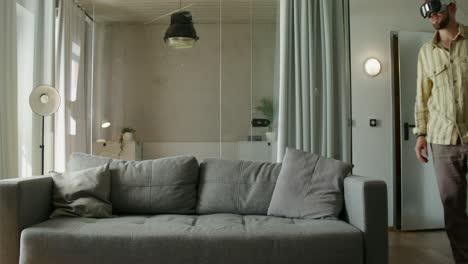 man wearing vr headset sitting on a couch in a modern living room