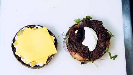 Veggie food. Cook making meatless hamburger on white background. Chef&#039;s hands make black burger with organic components. Cooking process step by step