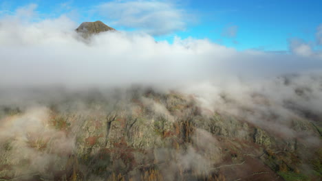 Mountaintop-peeking-out-of-cloud-layer-lit-by-early-morning-autumn-sunshine