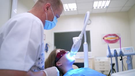 woman patient is treating her teeth at dentist's. modern technology at dentistry. stomatologist using new equipment while caring of patient's teeth.