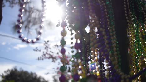 sunny outdoor mardi gras beads on light post in sunshine blowing in wind