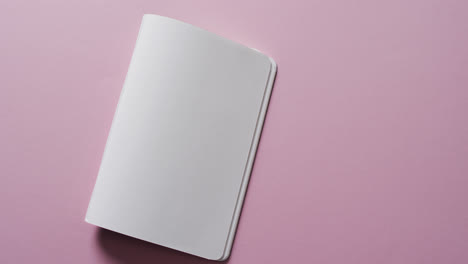 close up of open blank book with copy space on pink background in slow motion