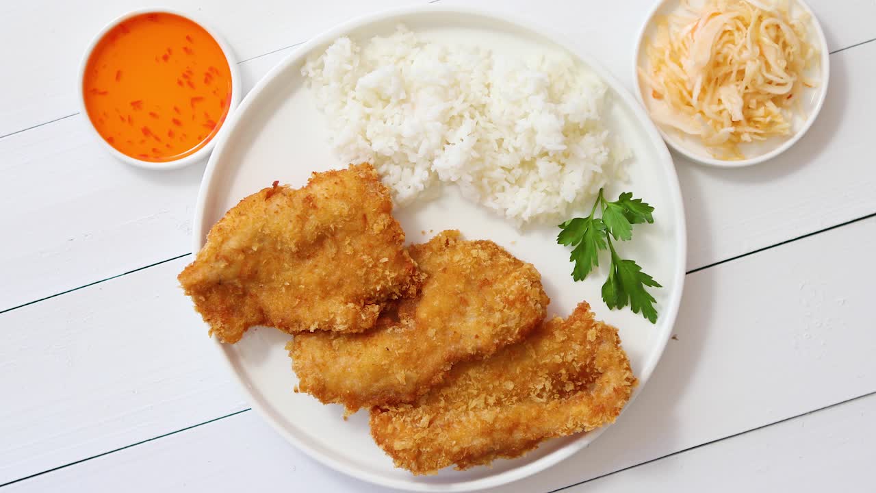 빵가루에 튀긴 바삭한 치킨은 흰색 나무 배경 위에 있는 쌀 전망과 함께 제공됩니다.