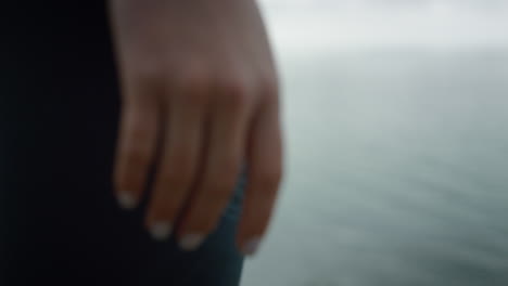 Closeup-fit-woman-hand-on-calm-sea-view.-Girl-standing-hill-on-morning.