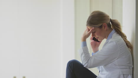 Stressed-Male-Doctor-Wearing-White-Coat-Sitting-At-Desk-In-Office