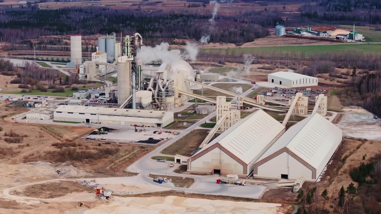 Large cement factory complex with silos, production buildings countryside Latvia