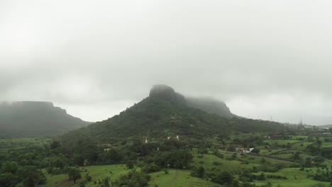 Die-Drohnenkamera-Bewegt-Sich-über-Die-Hügel-In-Richtung-Der-Berge,-Zwischen-Denen-Viel-Nebel-Herrscht