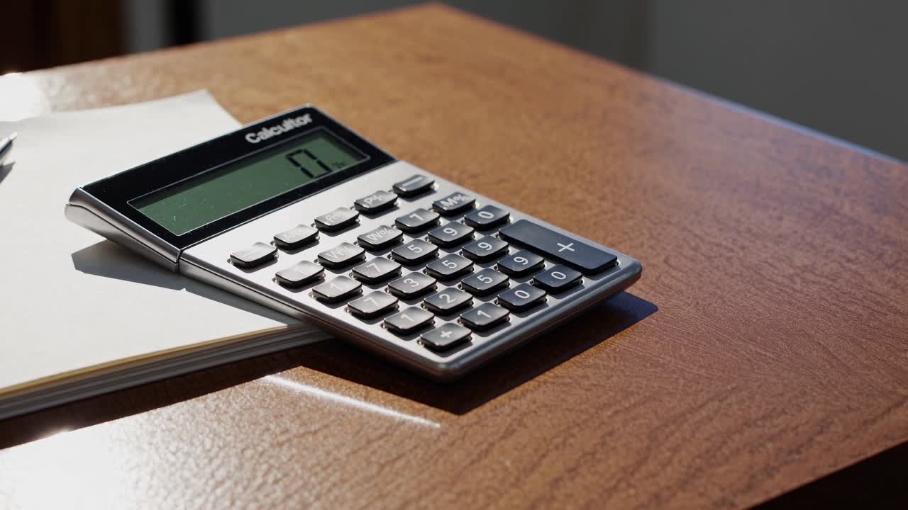 Close-up video shot of a calculator on a wooden desk, angled slightly from above