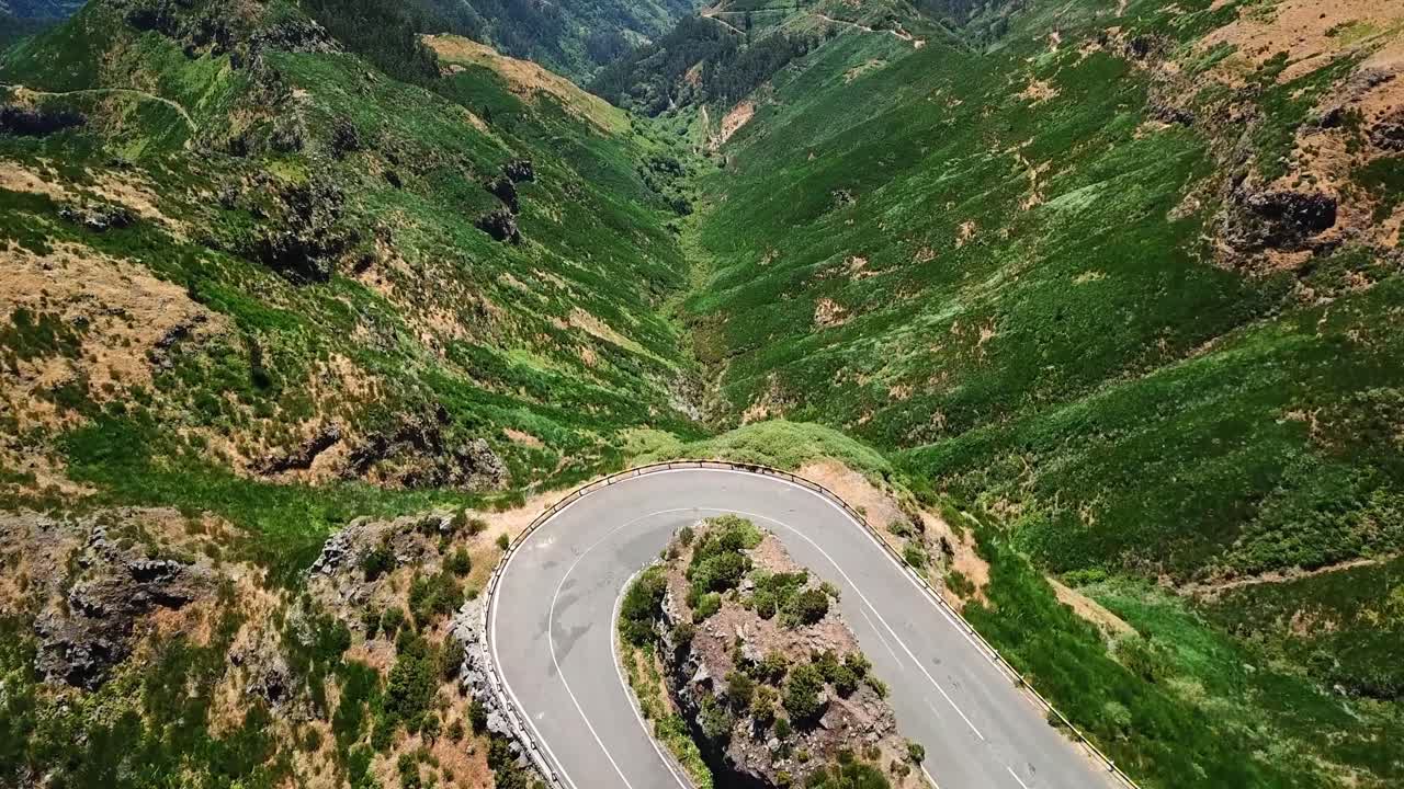 Aerial view of a scenic winding road making a hairpin turn in the lush green mountains, showcasing a breathtaking landscape, Miradouro Lombo do Mouro, Madeira, Portugal,
