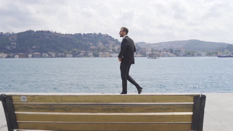 Unhappy-businessman-walking-by-the-sea.