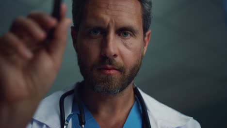 el médico chequeando con una linterna retrato de prueba. trabajador de la salud masculino serio.