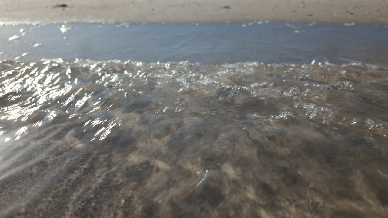 Calm underwater view showing sand ripples and light reflections beneath the sea surface