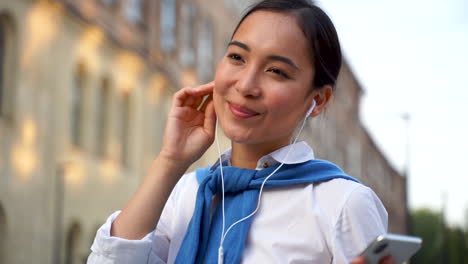 Cheerful-Woman-Listening-To-Music-With-Earphones-And-Walking-Down-The-Street