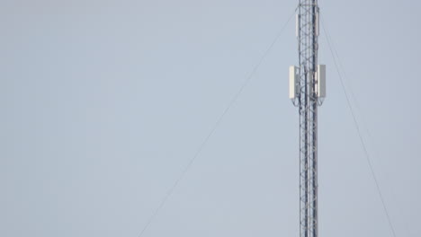 tilt-up reveal of tall mobile phone mast structure against sky, copy space