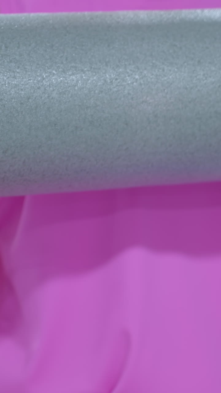 primer plano de una mano de mujer sosteniendo una espuma de rodillo, con un anillo en su dedo, mientras empuja hacia adelante, con una vista parcial de otra persona en el fondo en un entorno de gimnasio