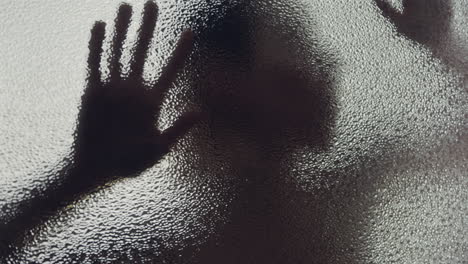 a female silhouette behind the frosted glass moves slowly