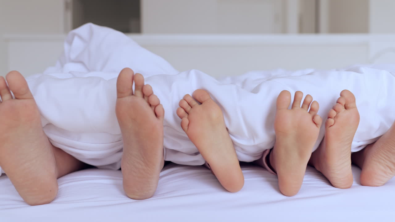 Familia, cama y pies con sábana