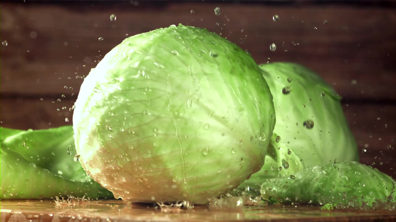 Verse groene kool met opspattende waterdruppels in slow motion