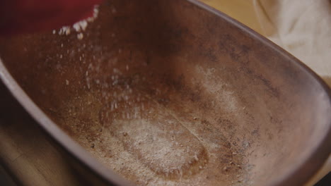 BAKING---Sprinkling-flour-on-a-clay-baker,-sourdough-bread-baking,-slow-motion