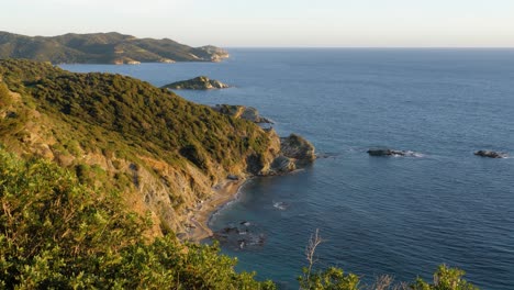 slow motion shot of stunning rocky coastline with vegetation in afternoon sun and blue water in chia, southern sardinia, italy