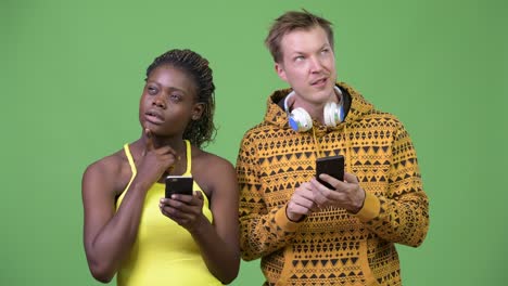 una joven pareja multiétnica usando el teléfono juntos.
