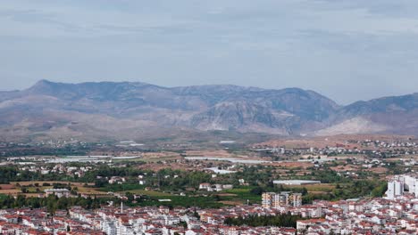 Aerial-view-approaching-the-Side-resort-town-neighbourhood-in-Turkey-and-South-eastern-mountain-range-on-the-horizon