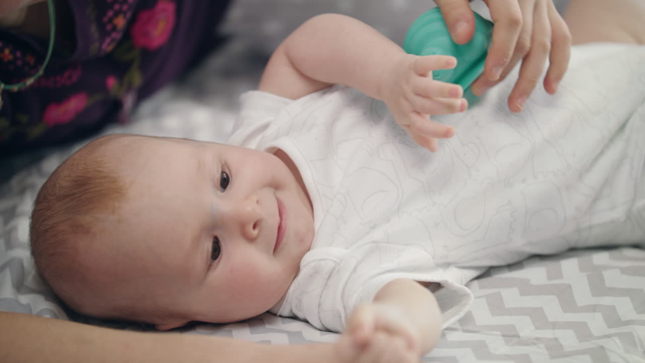 Active baby lying on back in bed. Adorable baby boy trying overturn