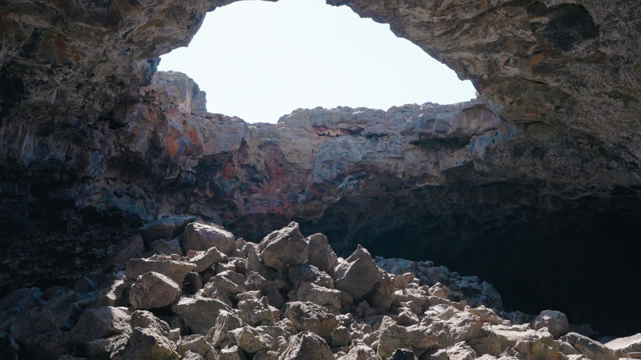 Sunlight streaming into a rocky cave entrance or lava tube