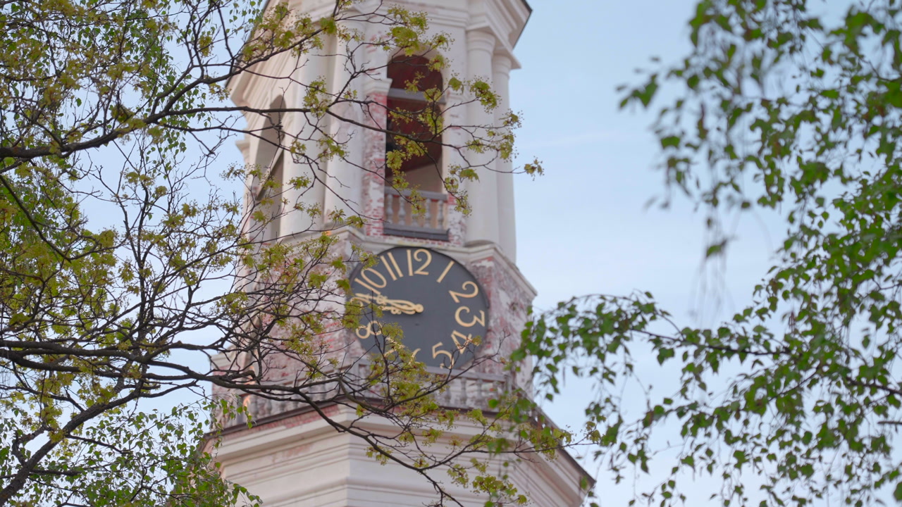 Bell Tower Clock Framed By Leaves, Close Drone Reveal Of Black Dial With Gold Numerals And Open Belfry Spring. Creative