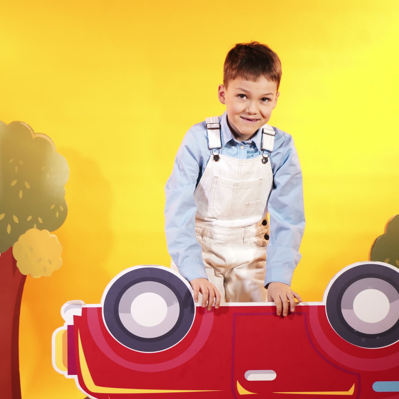 Little boy with a bright red car on a yellow background in the studio. Happy children. Square video