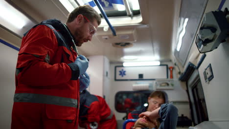 paramedic doctors examining patient on stretchers in emergency car