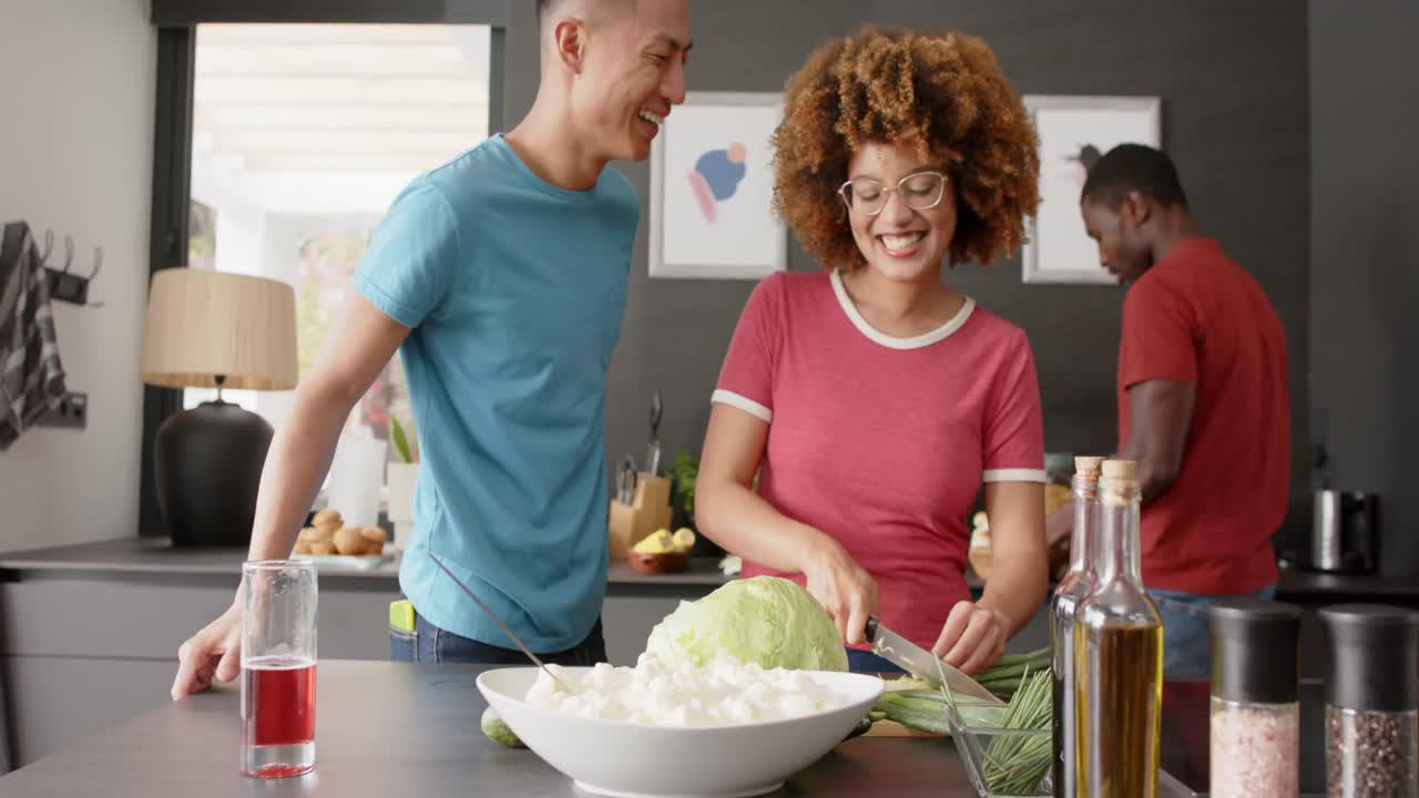 Happy diverse group of friends preapring meal in kitchen, slow motion