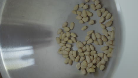 nueces de pino y aceite de oliva en un cuenco de acero inoxidable para pesto italiano fresco
