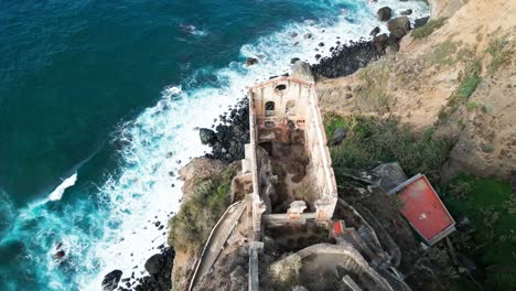 Drone-footage-captures-Elevador-de-Agua-de-Gordejuela,-an-ancient-cliffside-structure-in-Tenerife,-showcasing-its-historical-charm-against-the-backdrop-of-breathtaking-natural-landscapes