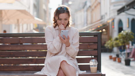 mujer joven usar teléfono inteligente móvil celebrando ganar buen mensaje de noticias al aire libre en la calle de la ciudad urbana