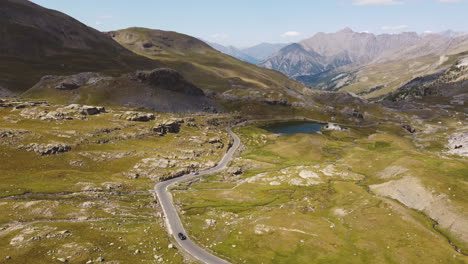 Langsam-Herabsinkendes-Dröhnen-Auf-Dem-Gipfel-Der-Alpen,-Eine-Straße-Führt-Zu-Einem-Tiefblauen-Bergsee