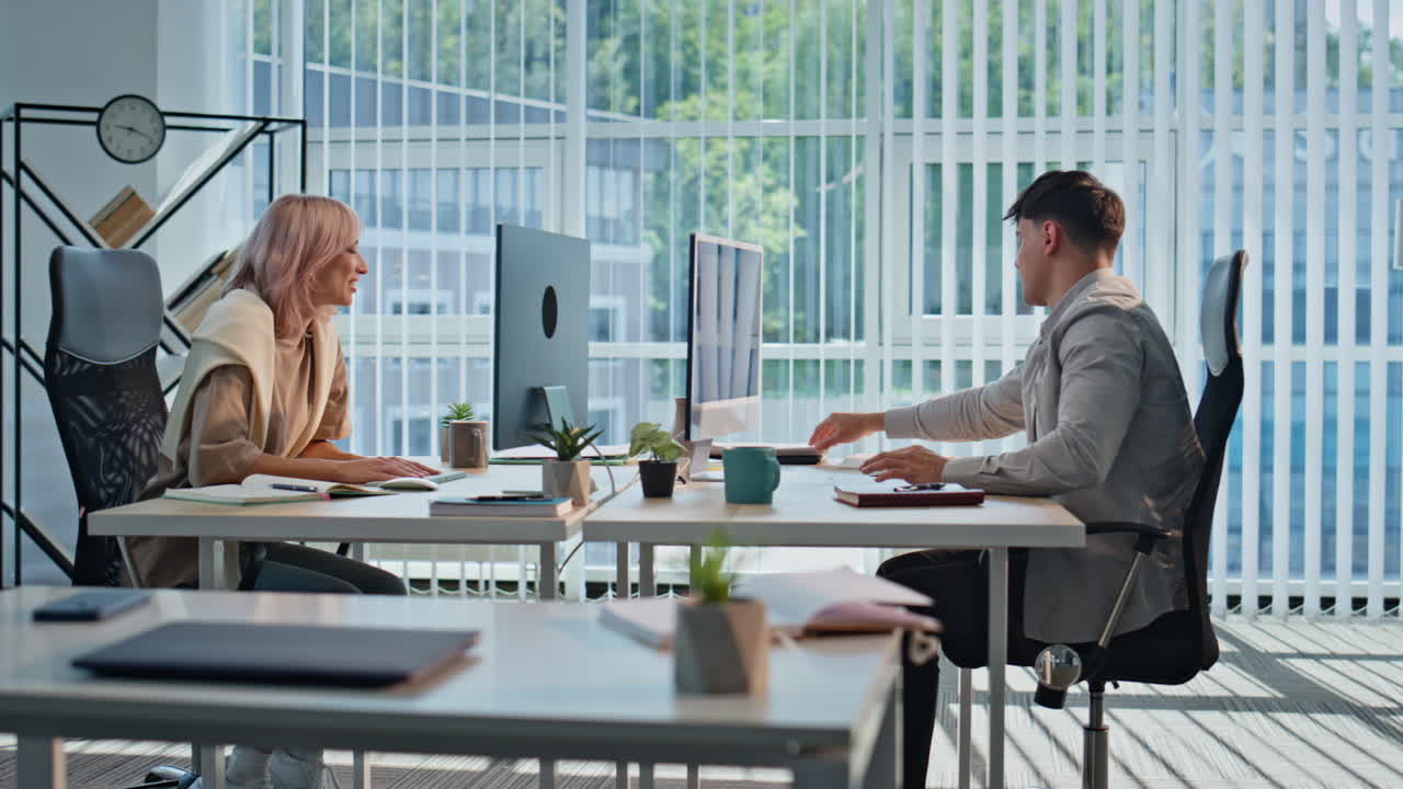 Two coworkers sharing ideas in coworking space. Couple smiling managers talking