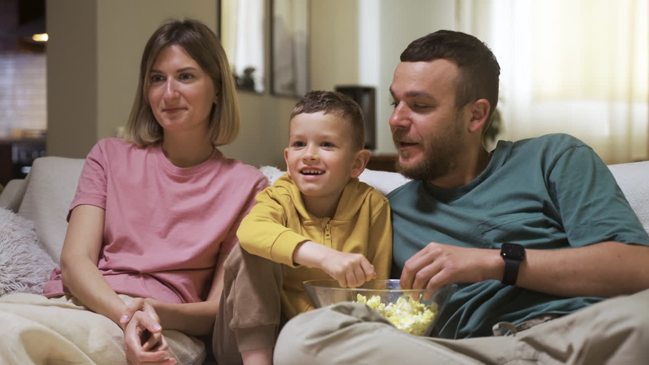 Famiglia seduta sul divano che guarda un film.