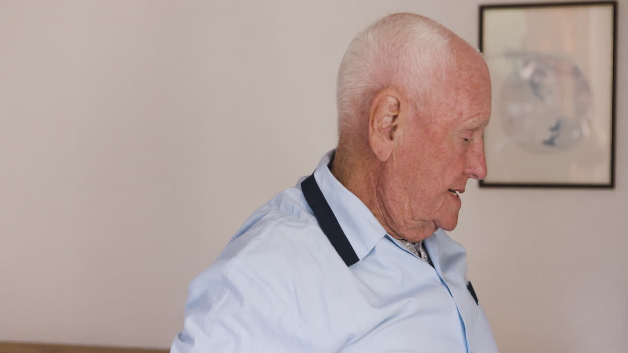 Elderly man getting dressed in bedroom
