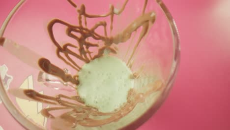 pouring steamed milk over mint ice cream inside a glass