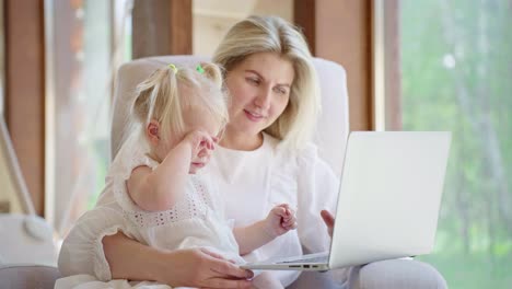 mother and toddler daughter using laptop