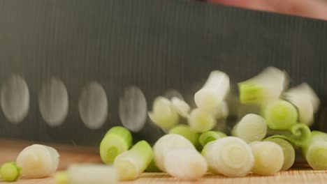 cutting fresh green onions on a cutting board, close up chef cooking green vegan salad.