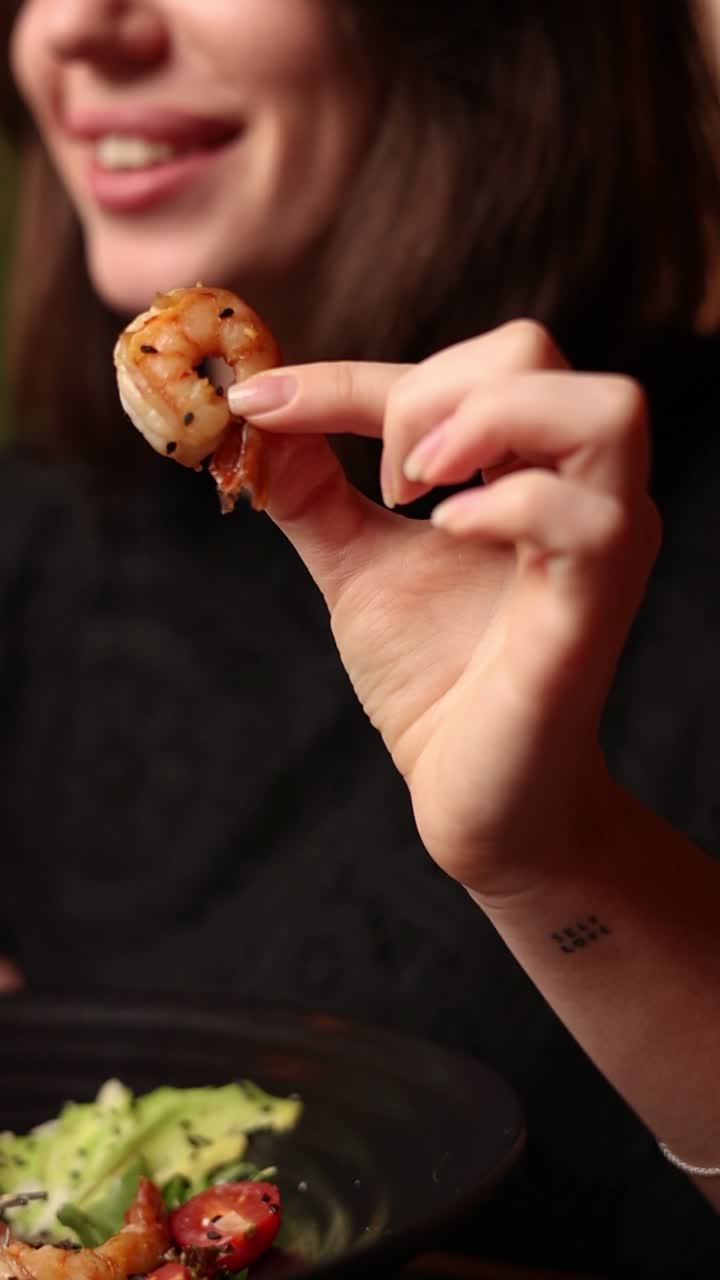 una mujer comiendo camarones.