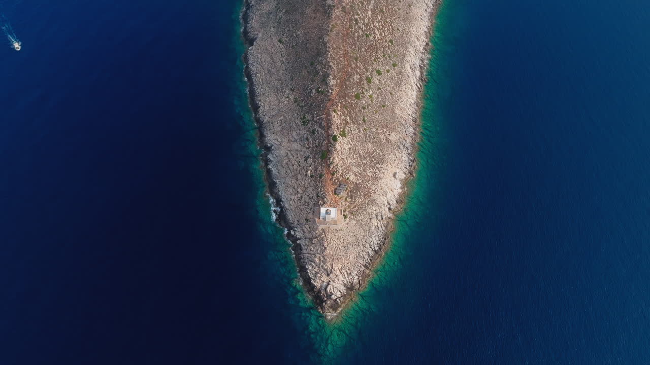 High angle aerial over Cape Tainaron as peninsula juts into sea, sharp cliffs and deep blue water