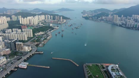 hong kong marina with anchored boats and kwun tong area buildings, aerial view