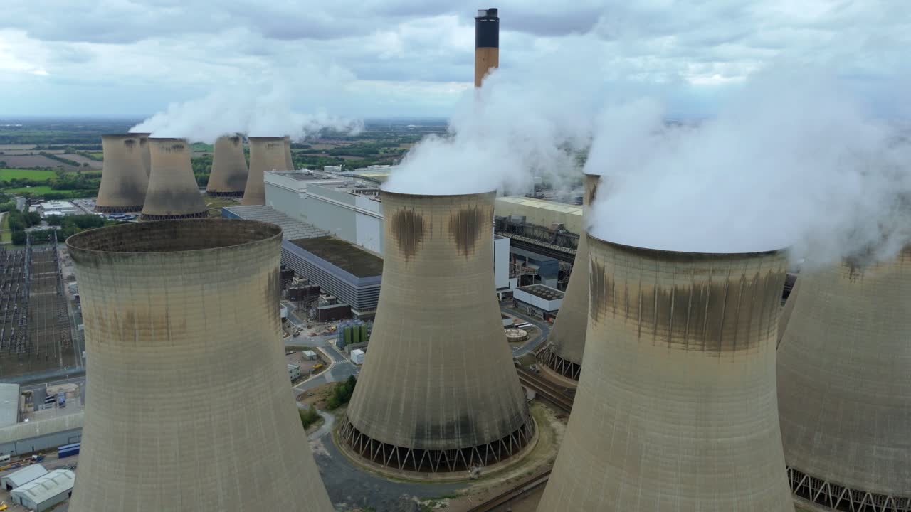 Aerial drone over huge power plant with cooling towers and smoke plumes near Selby Yorkshire United Kingdom
